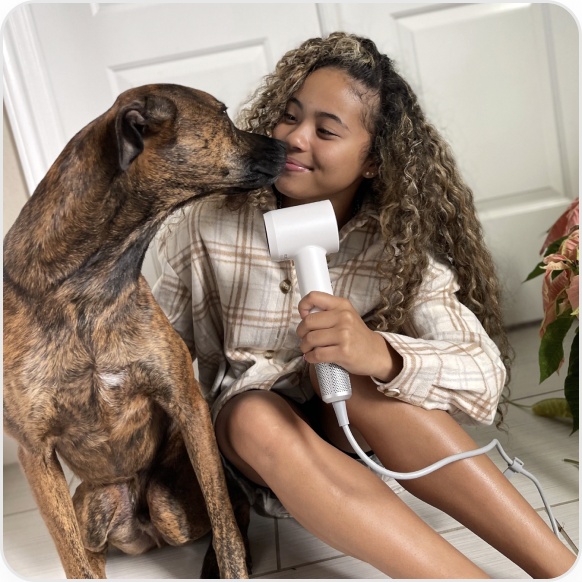 A girl is blowing her hair with Laifen products with a dog