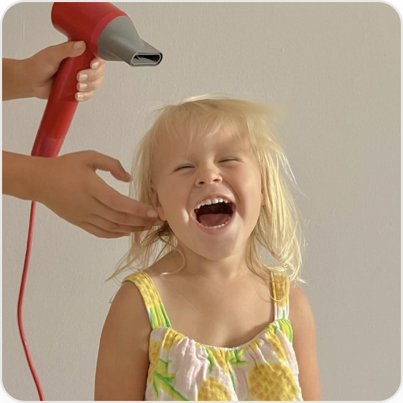 A kid is using Laifen hair dryer with a big smile