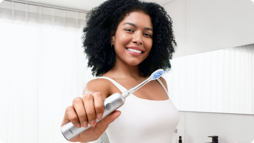 Black and white illustration of a person brushing their teeth in a bathroom.